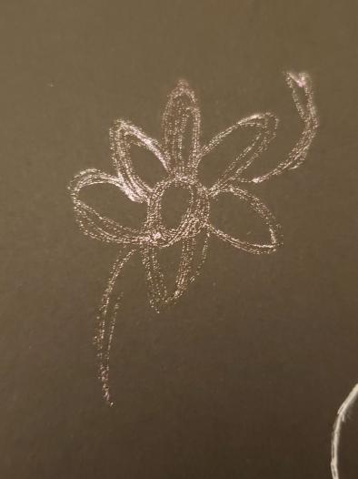 a gold and silver daisy on black paper