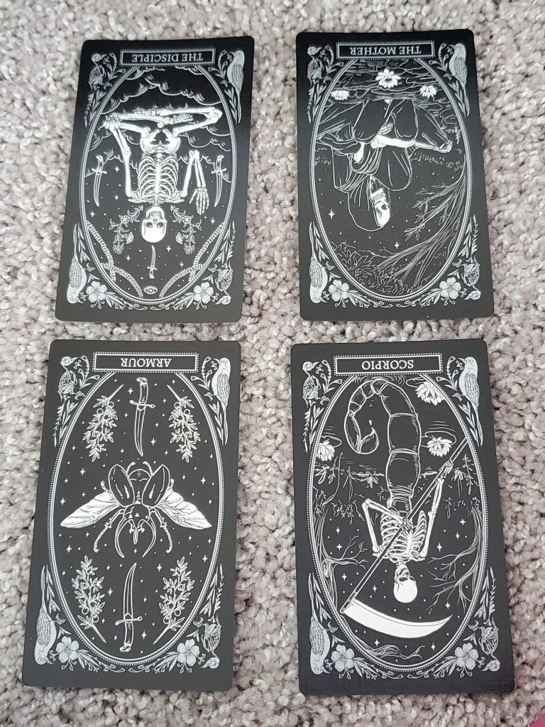 ID: four cards from the Mirror Oracle Deck are laid out in a square. the disciple, the mother, armour, and scorpio. all cards are reversed.