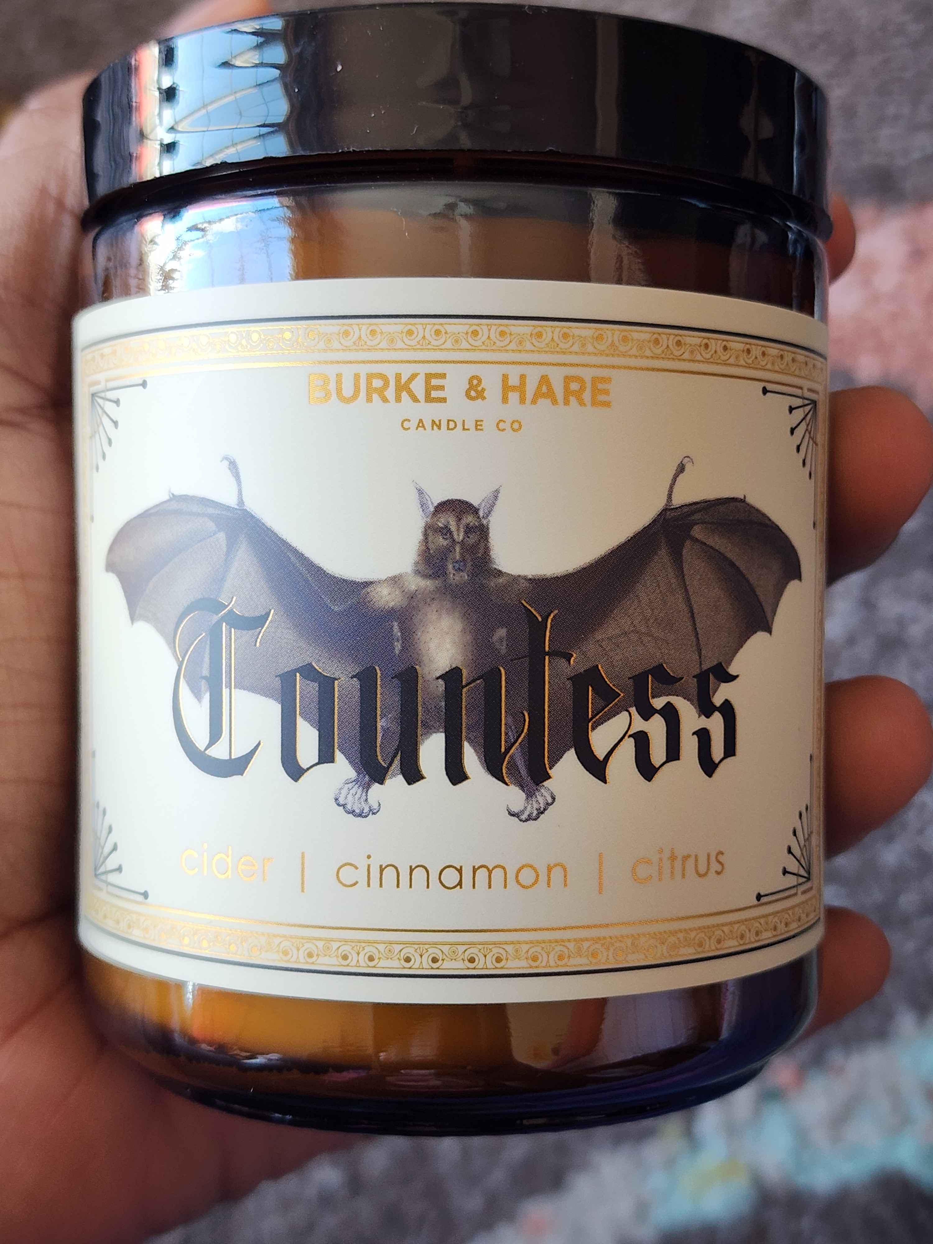 ID: an amber jar candle from Burke & Hare called Countess, with notes of cider, cinnamon, and citrus.