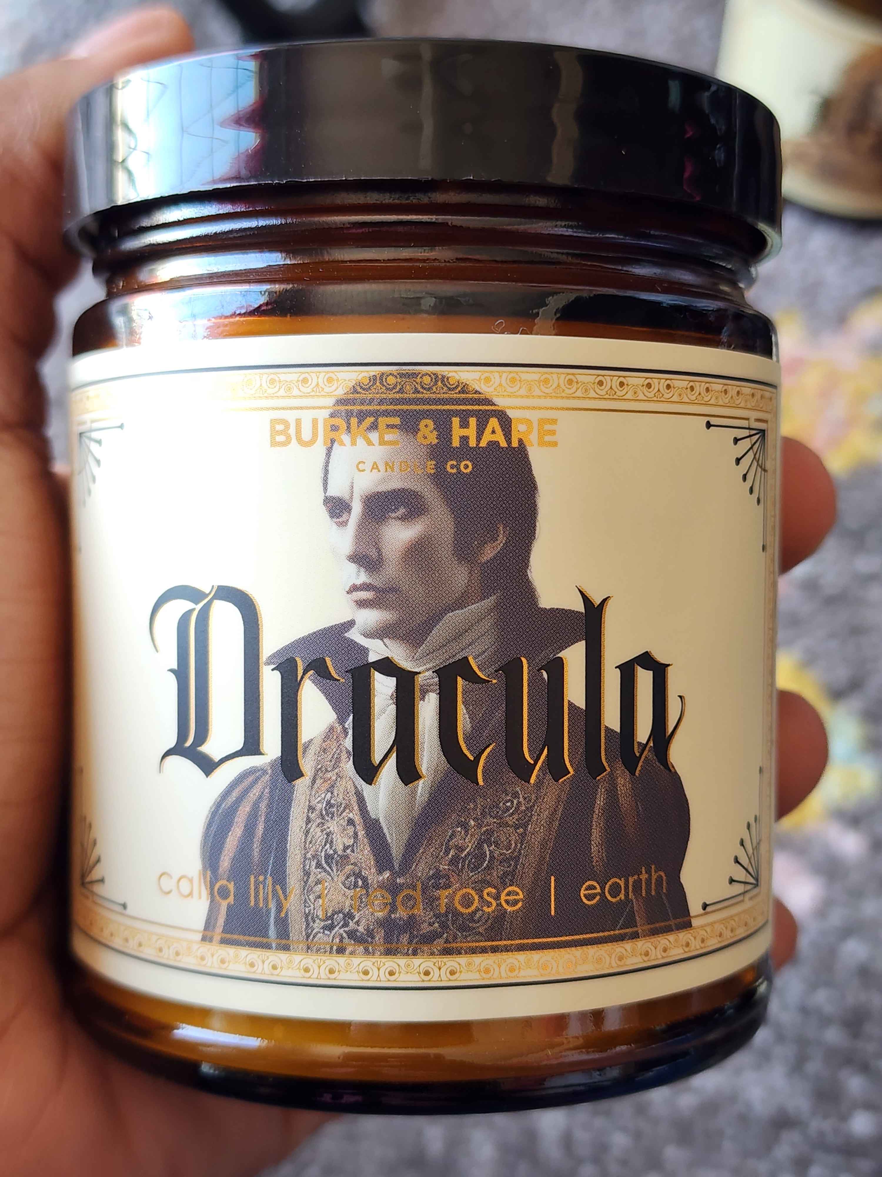 ID: an amber jar candle from Burke & Hare called Dracula, with notes of calla lily, red rose, and earth
