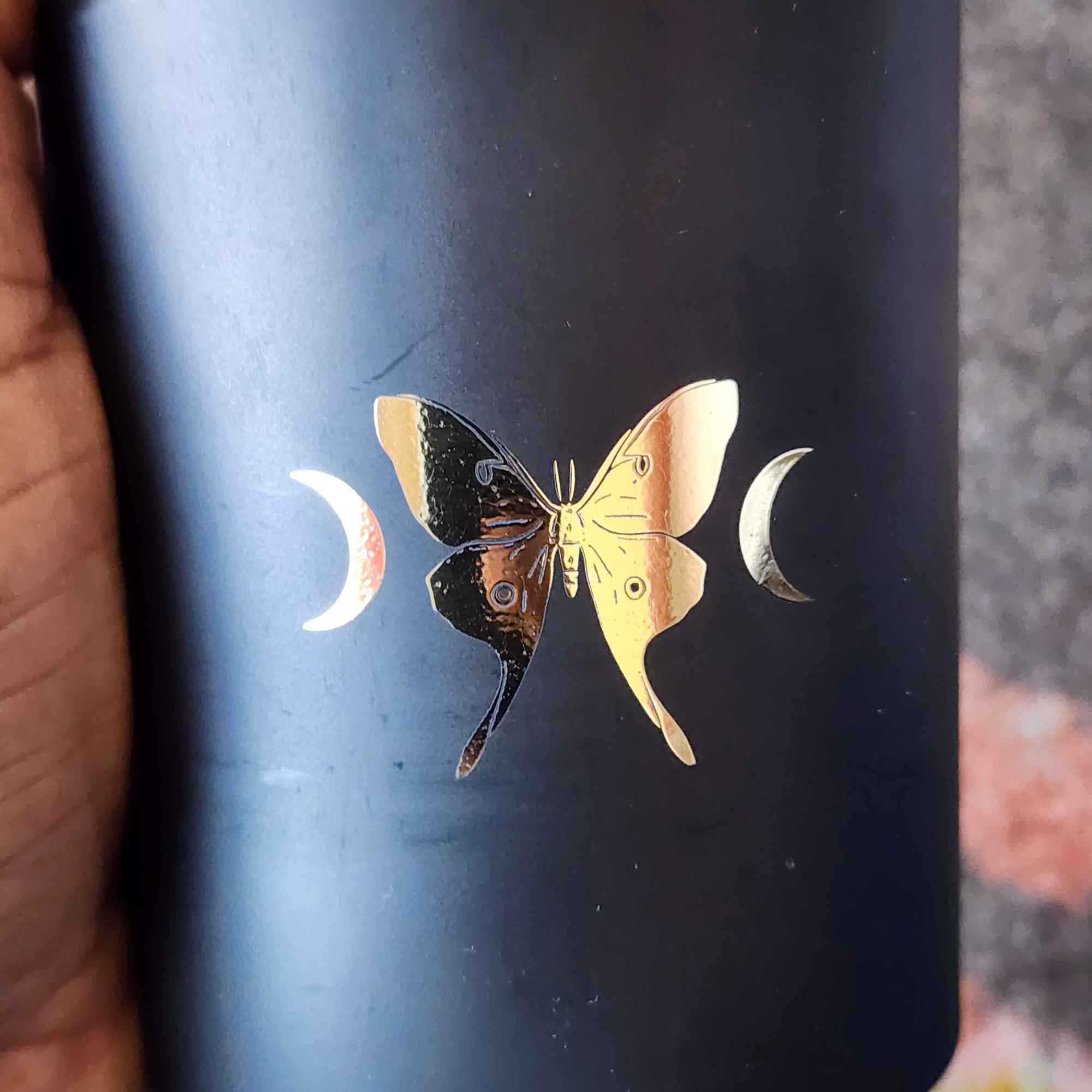 ID: a black jar candle from 13th Press called La Lune. a gold foil butterfly is on the jar, with crescent moons on either side 
