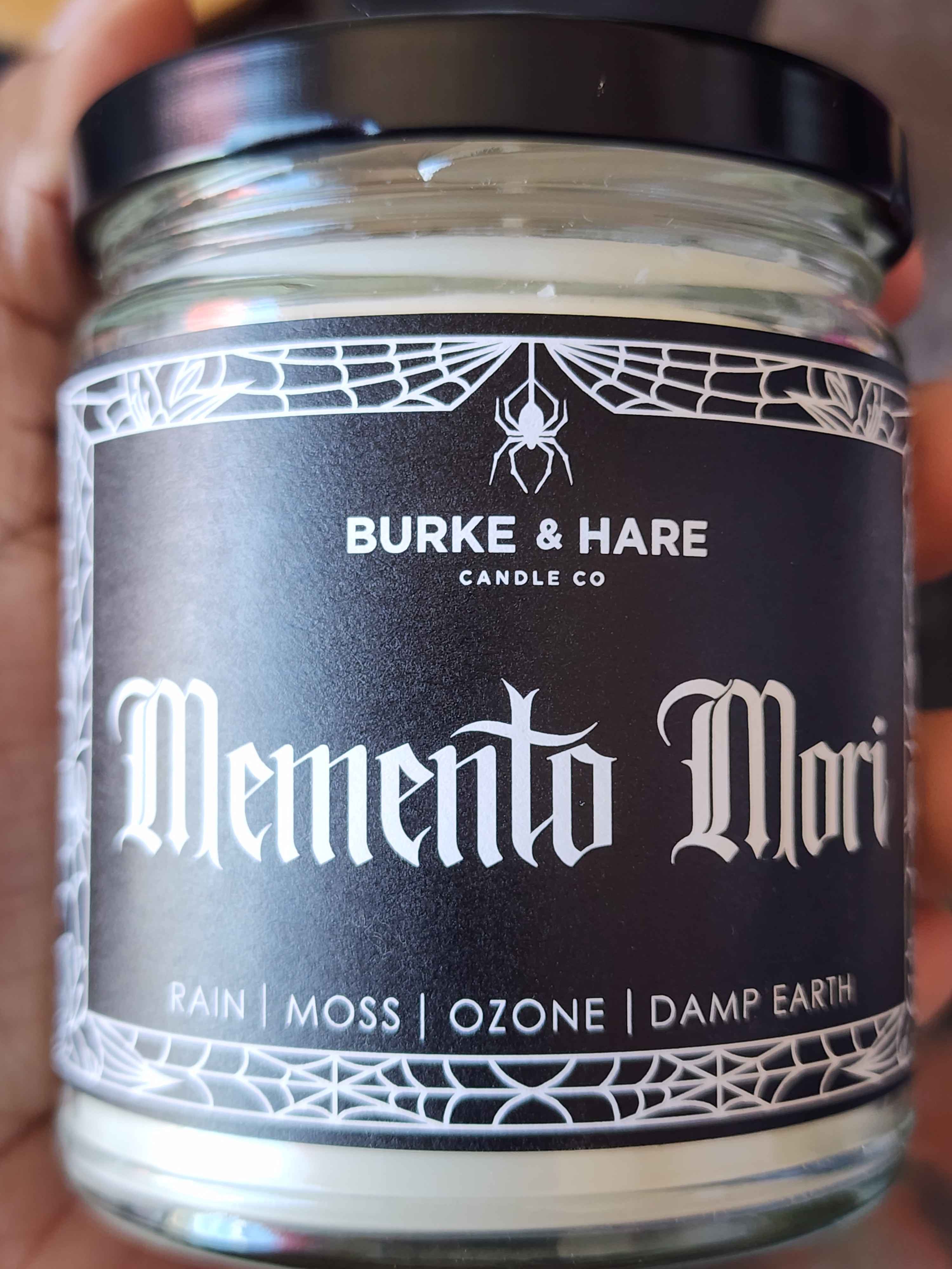 ID: a clear jar candle from Burke & Hare called Memento Mori, with notes of rain, moss, ozone, and damp earth