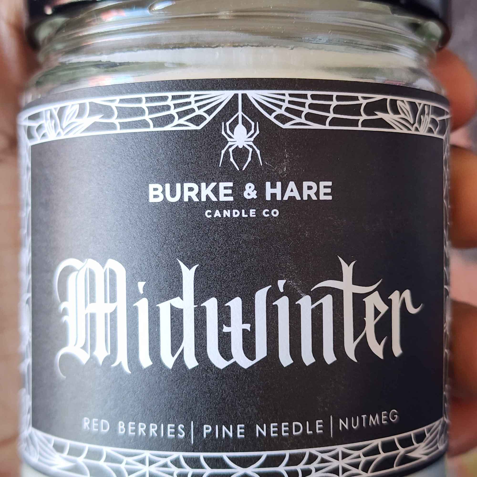 ID: a clear jar candle from Burke & Hare called Midwinter, with notes of red berries, pine needles, and nutmeg