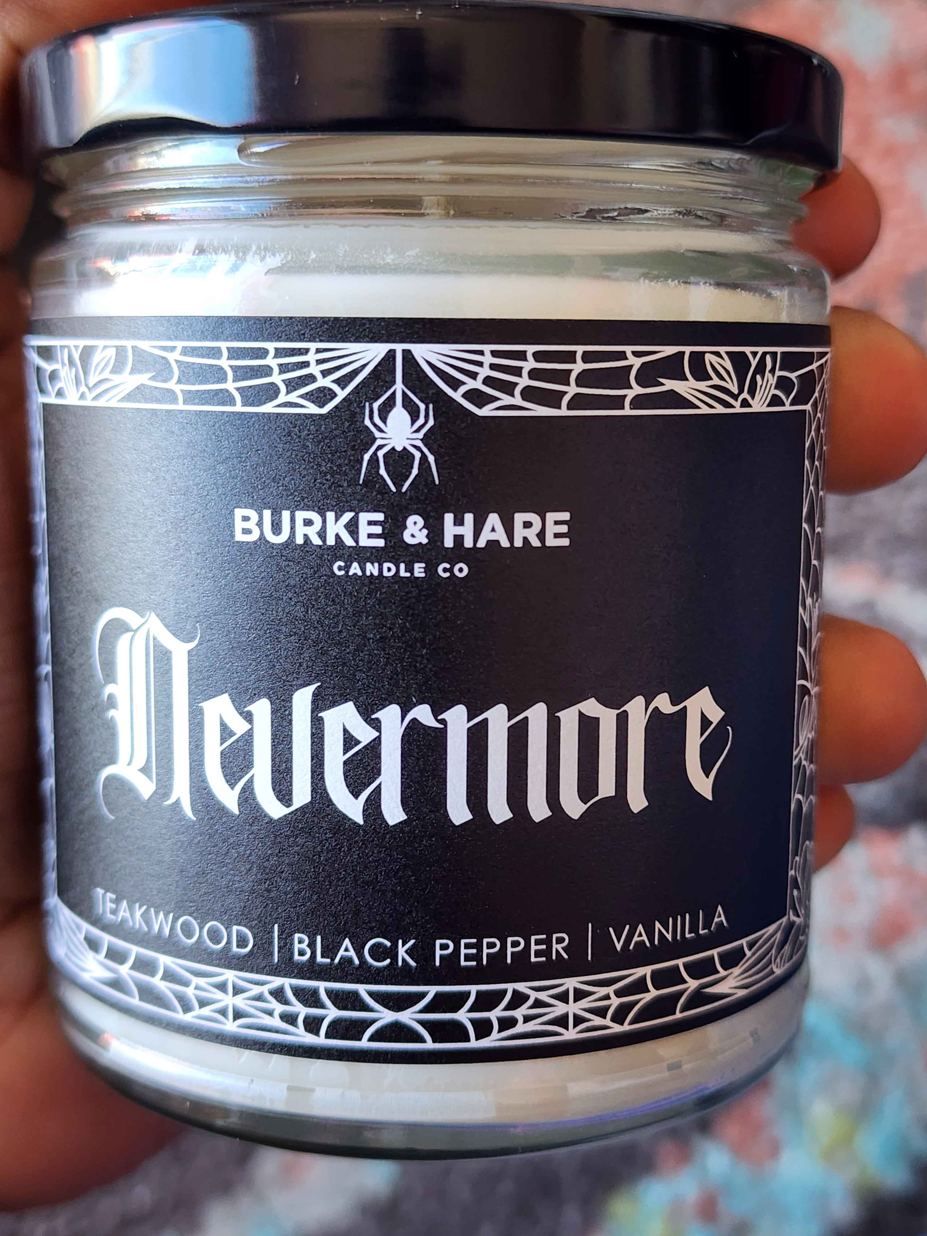 ID: a clear jar candle from Burke & Hare called Nevermore, with notes of teakwood, black pepper, and vanilla
