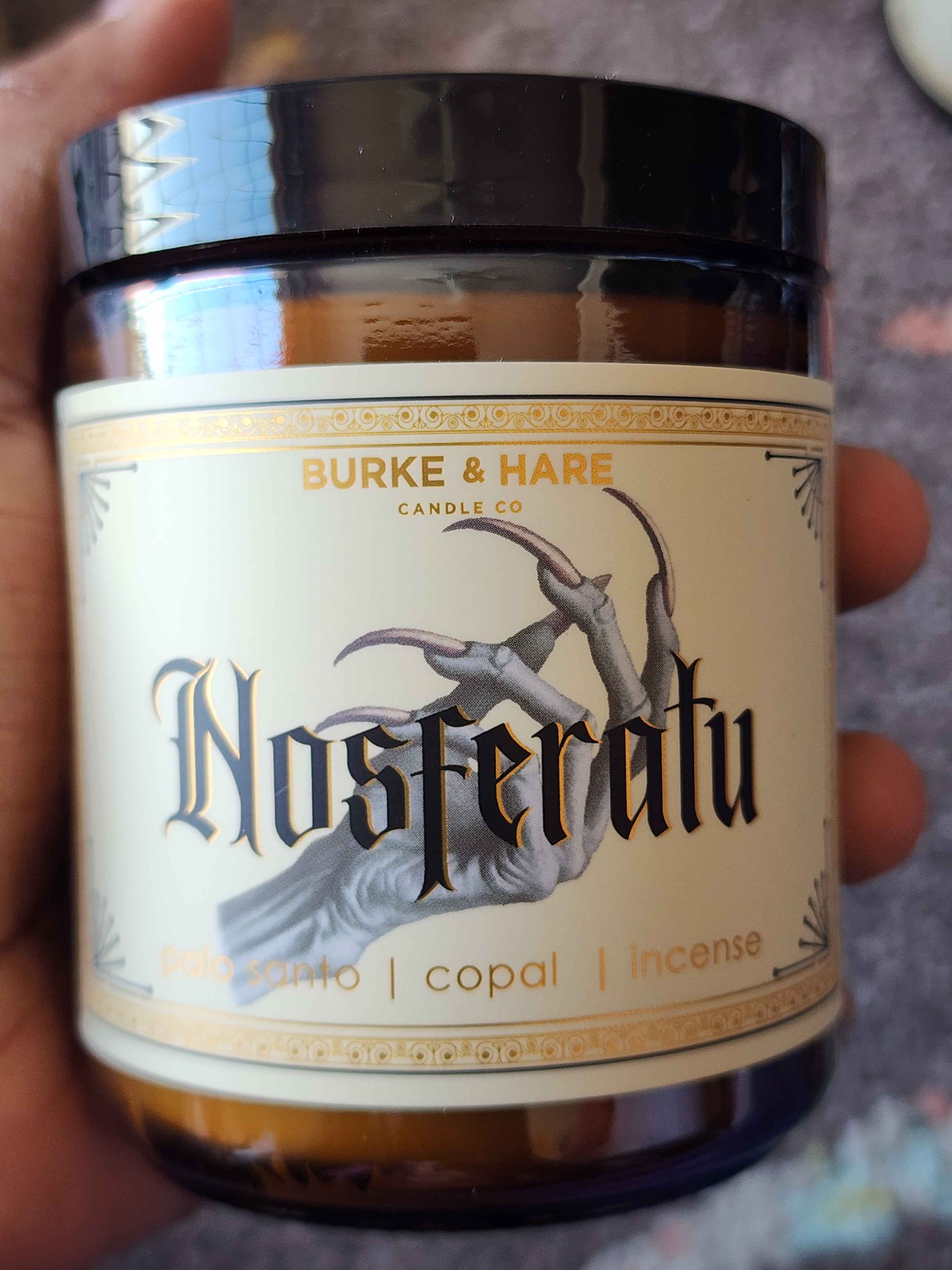 ID: a an amber jar candle from Burke & Hare called Nosferatu with notes of palo santo, copal, and incense