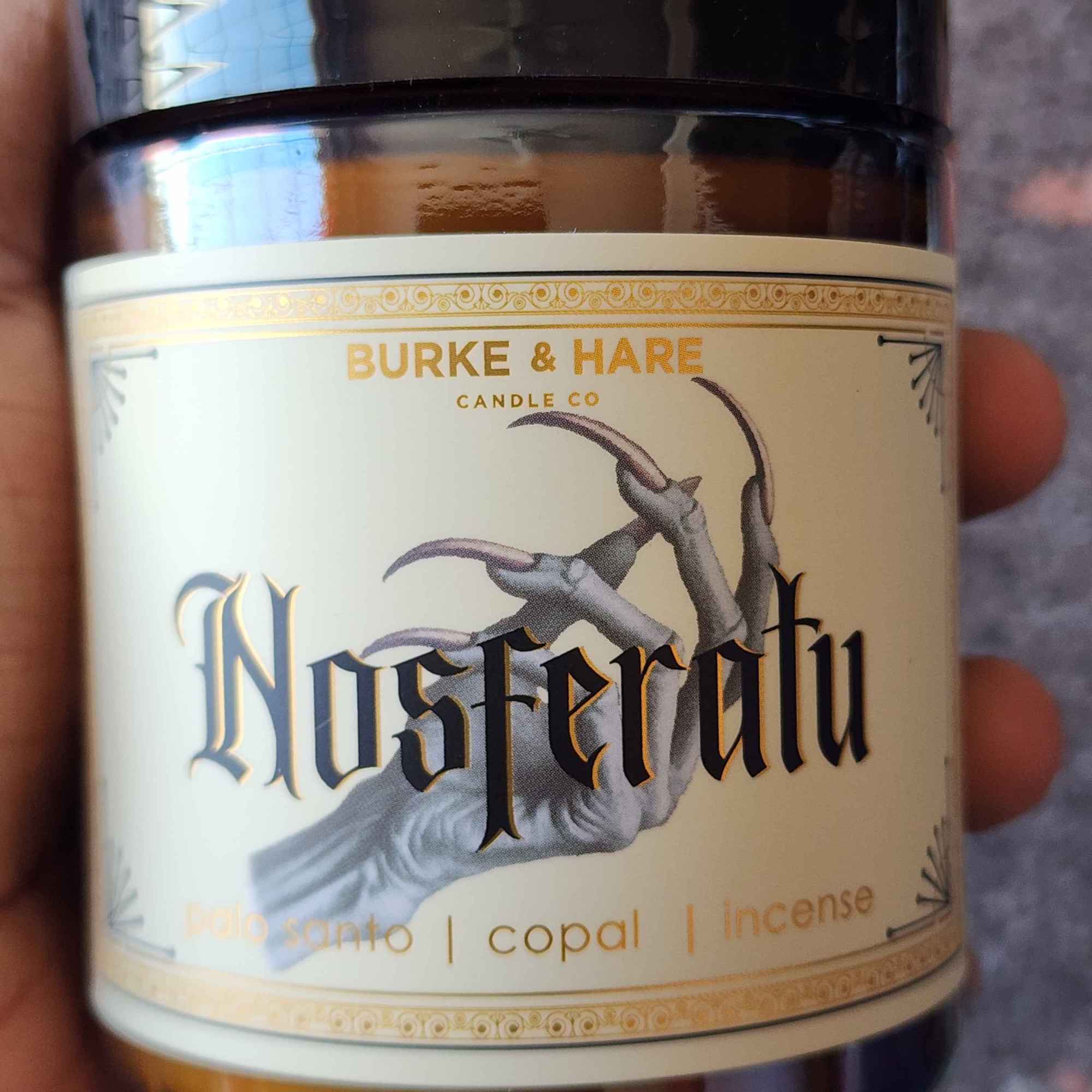ID: a an amber jar candle from Burke & Hare called Nosferatu with notes of palo santo, copal, and incense