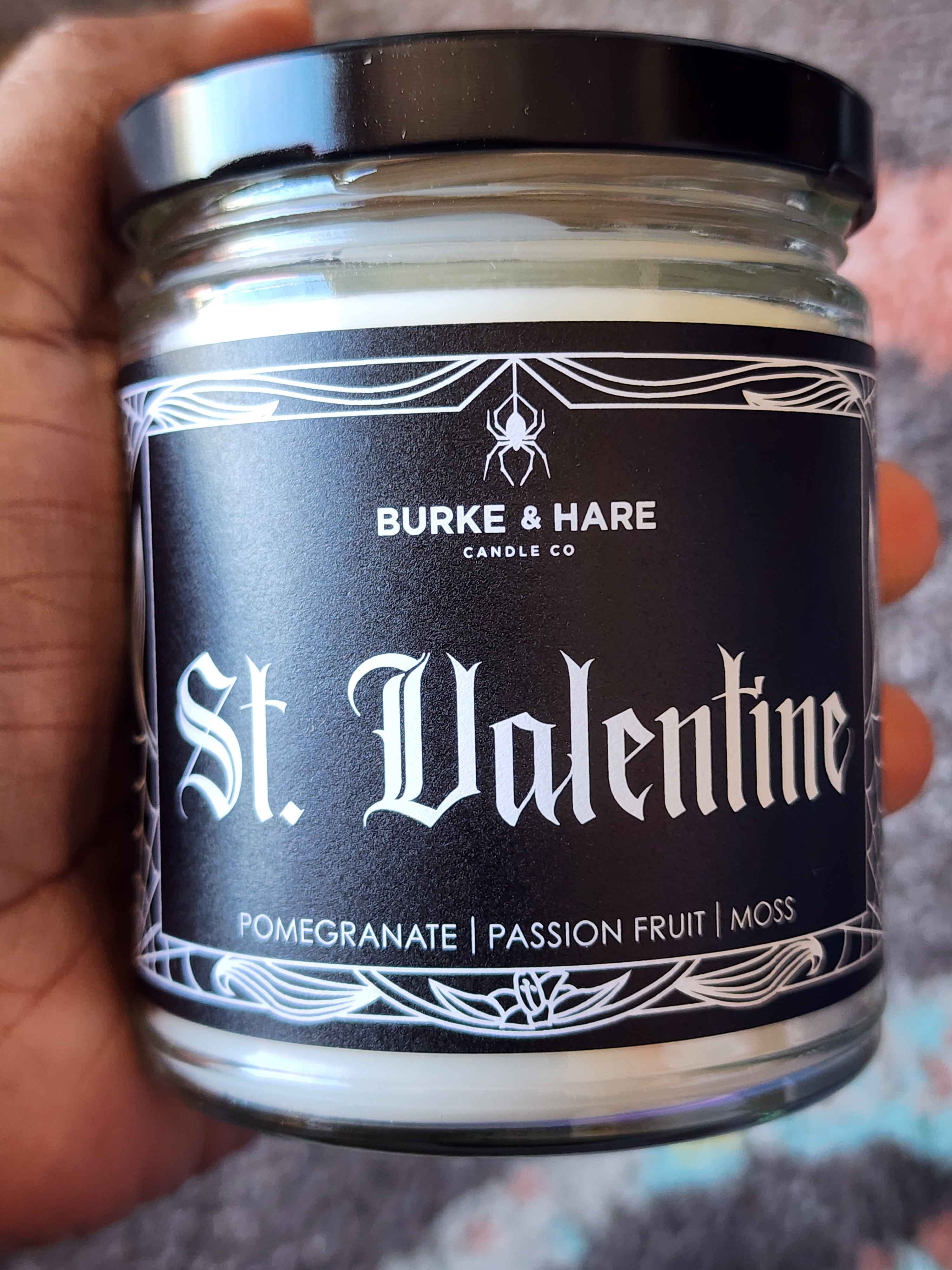 ID: a clear jar candle from Burke & Hare called Saint Valentine, with notes of pomegranate, passionfruit, and moss